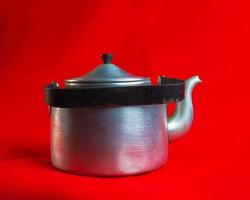 Old soldier's aluminum teapot from the Second World War on a red background. photo