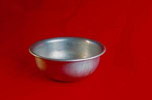 An old aluminum bowl made in circa 1960 against a red background. photo