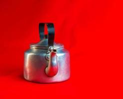 Old soldier's aluminum teapot from the Second World War on a red background. photo