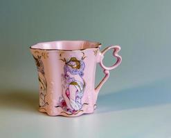 porcelana rosado taza de un raro forma es hecho en el checo república. un taza con un romántico modelo en un blanco antecedentes. foto