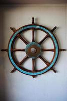 Old Metal Ship Steering Wheel Decoration on Concrete Wall. photo
