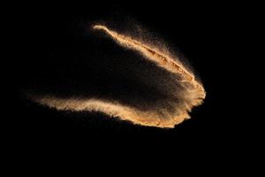 Brown color sand splash against black background. Sand fly wave in the air. photo