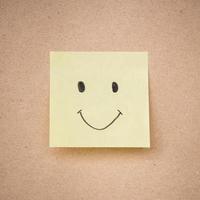 yellow sticky note smile on brown paper texture close up photo