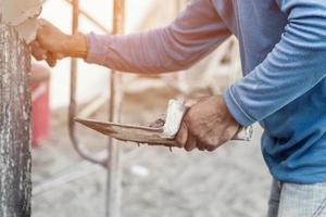 plasterer concrete worker at wall of home construction building photo
