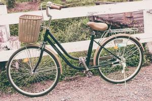 Clásico bicicleta en jardín y cerca madera foto