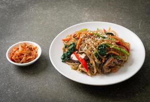 japchae or stir-fried Korean vermicelli noodles with vegetables and pork topped with white sesame photo