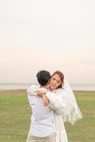 Happy young Asian couple in bride and groom clothing photo