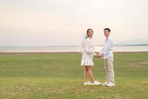 Happy young Asian couple in bride and groom clothing photo