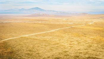 aéreo tranquilo panorámico ver a vasto amarillo césped campos con hermosa montañas antecedentes. vashlovani nacional parque apagado el vencido pista ubicaciones. foto