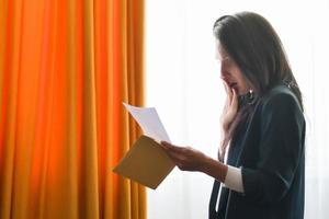 Woman surprised open read high bills by window photo