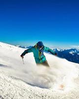 Georgia, 2022 - Professional skier at full speed ski downhill on fresh snow do carving in ski resort while training for competition in ski resort with mountains background photo