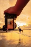 A camera photographs an Asian woman doing a ballet dance lonely on the beach photo