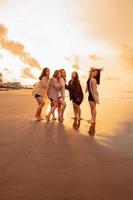 un grupo de asiático mujer en camisas posando felizmente mientras visitando un hermosa playa foto