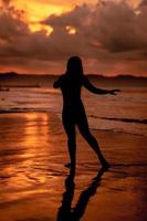 silhouette of an Asian woman dancing ballet with great flexibility and a view of the waves behind her photo