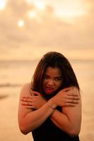 an Asian teenager relaxing on the beach wearing black clothes and posing beautifully photo