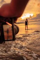 A camera photographs an Asian woman doing a ballet dance lonely on the beach photo