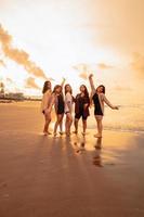 un grupo de asiático mujer en camisas posando felizmente mientras visitando un hermosa playa foto