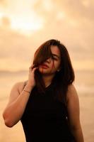 an Asian teenager relaxing on the beach wearing black clothes and posing beautifully photo