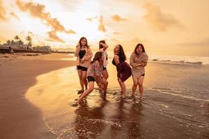 un grupo de asiático mujer disfrutando su fiesta muy loco con su amigos y con un lleno expresión de tontería en el playa foto