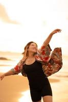 An Asian woman with blonde hair and a red shirt walks along the beach to enjoy the sea view photo