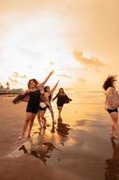 a group of Asian teenagers running with happy expressions on vacation with their friends drunk on the beach photo