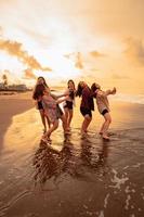 un grupo de indonesio mujer disfrutar el playa felizmente cuando ellos reunirse su amigos a el fiesta momento foto