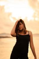 An Asian woman in a black dress with a very sexy expression attracts the attention of people around the beach photo