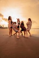 un grupo de indonesio mujer disfrutar el playa felizmente cuando ellos reunirse su amigos a el fiesta momento foto