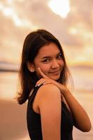 an Asian teenage woman with a black shirt and black hair has a cute face when she smiles and enjoys the view photo