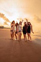 un grupo de indonesio mujer disfrutar el playa felizmente cuando ellos reunirse su amigos a el fiesta momento foto