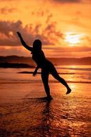 silhouette of an Asian woman dancing ballet with great flexibility and a view of the waves behind her photo