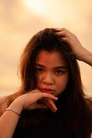 an Asian woman with blonde hair is posing by holding her head on the beach photo