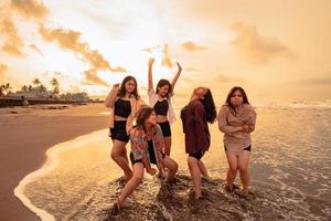 un grupo de asiático mujer disfrutando su fiesta muy loco con su amigos y con un lleno expresión de tontería en el playa foto