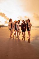 a group of Asian women in shirts posing happily while visiting a beautiful beach photo