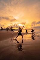 a group of Asian women is standing on the beach in black clothes and doing ballet moves in unison photo