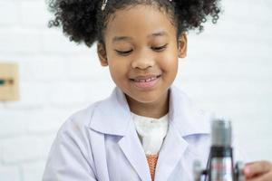 encantador pequeño niña científico disfrutar y excitar a examinar el color químico en laboratorio por utilizando cuentagotas con día ligero. emocionado niño celebrando terminado exitoso Ciencias experimentar resultado o químico foto