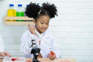 Lovely little girl scientist enjoy and excite to examine the color chemical in laboratory by using dropper with day light. Excited Kid celebrating over successful science experiment result or chemical photo