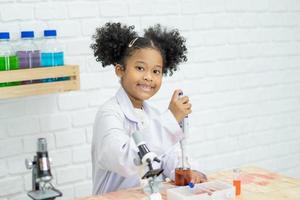 Lovely little girl scientist enjoy and excite to examine the color chemical in laboratory by using dropper with day light. Excited Kid celebrating over successful science experiment result or chemical photo