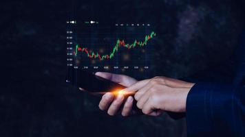 Businessman touching points smartphone with checking trend chart growing up, symbol stock graph and chart background, concept growth and development business investment photo