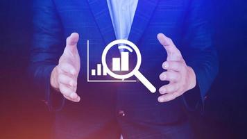 Businessman showing business growth on graph Hands touching graphs representing increasing profits with virtual interface technology, financial symbols coming photo