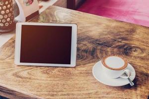 coffee and tablet computer on table with vintage tone. photo