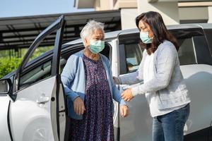 Caregiver help and support asian senior or elderly old lady woman patient walk with walker prepare get to her car, healthy strong medical concept. photo