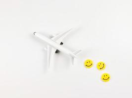 flat lay of airplane model with three yellow circle smiling faces  on white  background. Happy or fun trip concept. photo