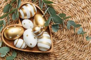 Easter decor. Easter eggs painted in gold in a heart-shaped wooden bowl. photo