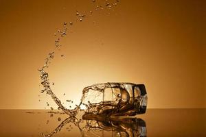 Falling glass of alcoholic drink on a golden background photo