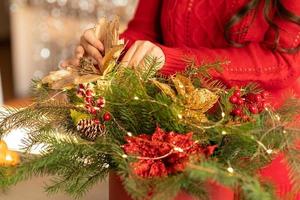 girl collects a Christmas bouquet of fir branches, flowers and Christmas tree decorations