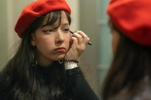 Young elegant girl doing her makeup with eyeliner photo