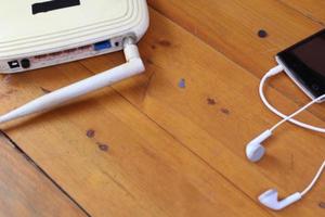 cut out wifi router, smart phone and earphones on wooden table.  technology concept photo