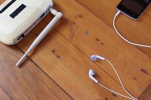 cut out wifi router, smart phone and earphones on wooden table.  technology concept photo