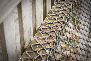 Fabric weaved rope net hanging on wooden plank near wet concrete wall weird urban findings photo
